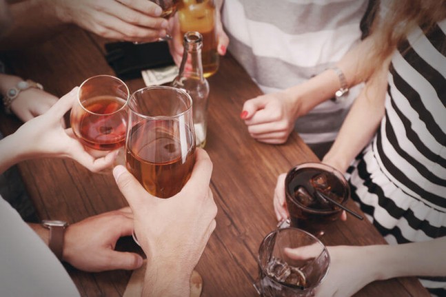 top view of hands holding alcoholic drinks at a bar