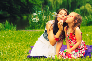 mother and little girl daughter child blowing soap bubbles outdoor. parent and kid having fun in park. happy and carefree childhood. good family relations.