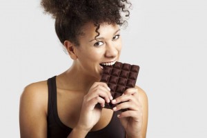 Beautiful african woman holding and eating a huge dark chocolate bar