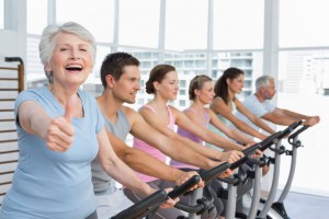 Woman gesturing thumbs up with class working out in the gym