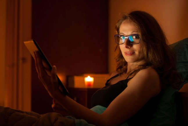woman watching tablet with glasses on at night
