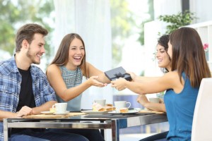 Friends celebrating birthday and giving gift to a girl sitting in a dining room