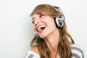 Beautiful young brunette listening to music with headphones, laughing