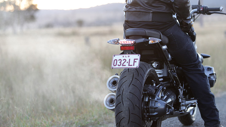 Rear view of rider mounted on a BMW motorcycle with steam coming out of the exhaust.