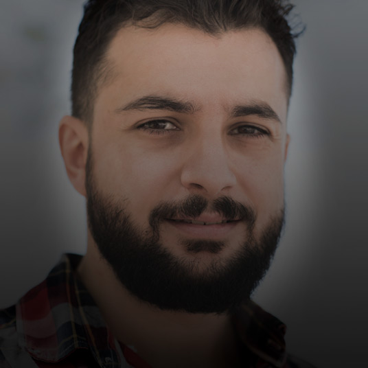 Portrait of young man with beard smirking at camera