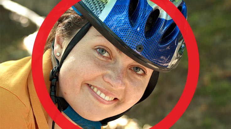 Portrait of lady with bicycle helmet on smiling at camera with thick red circle framing her face