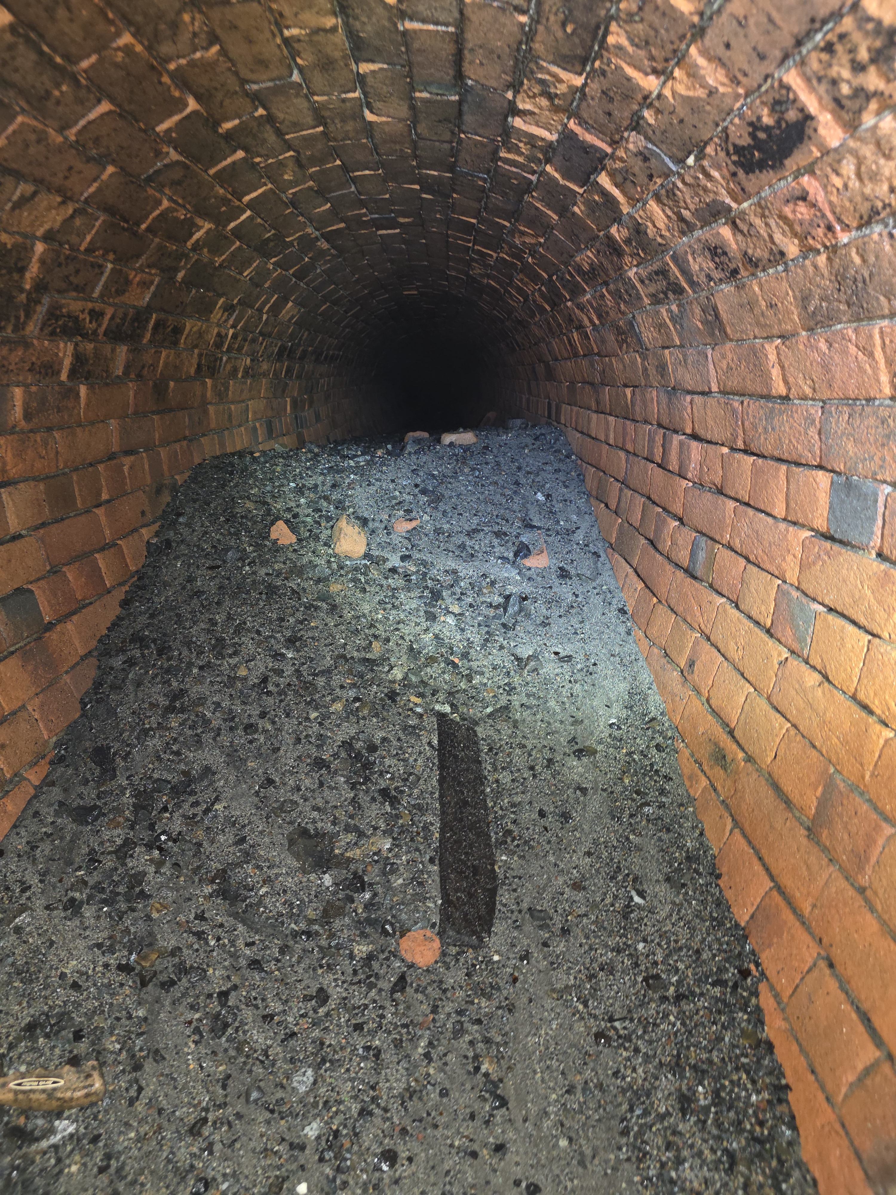 Brick stormwater line with pile of debris made up of sand, gravel and other materials