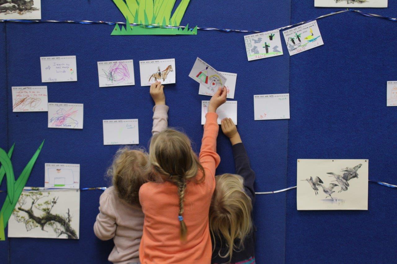 Photograph of children pinning their ideas for the Ōtākaro Avon River Corridor Regeneration Area onto a community noticeboard.