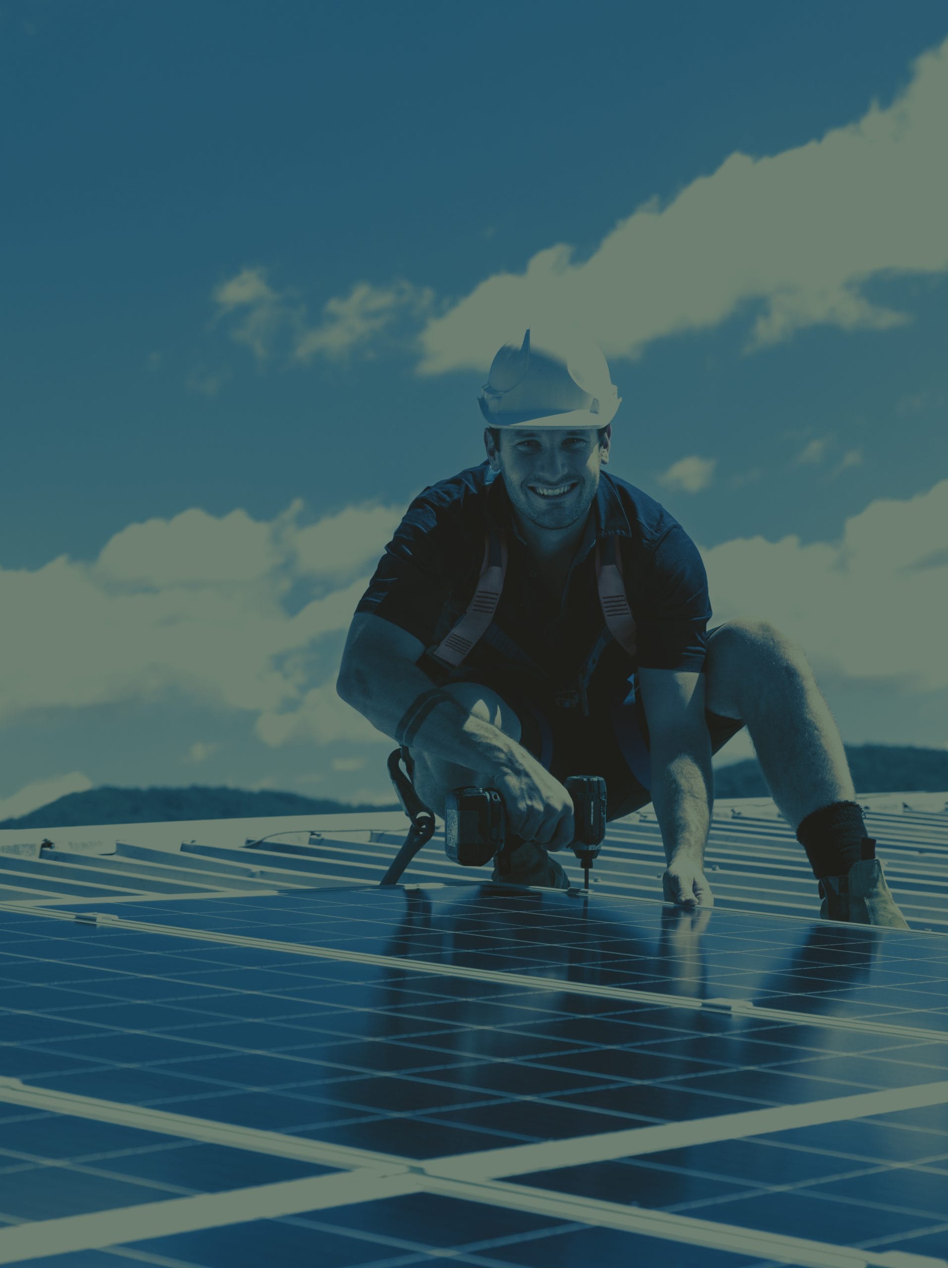 Solar panel technician with drill installing solar panels on roof on a sunny day