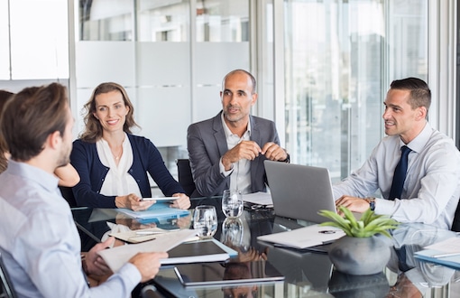 Business meeting Multiethnic group of business people sitting in annual meeting in conference room. Mature leader with businessmen and businesswomen discussing. Busy partners working together in modern office.
