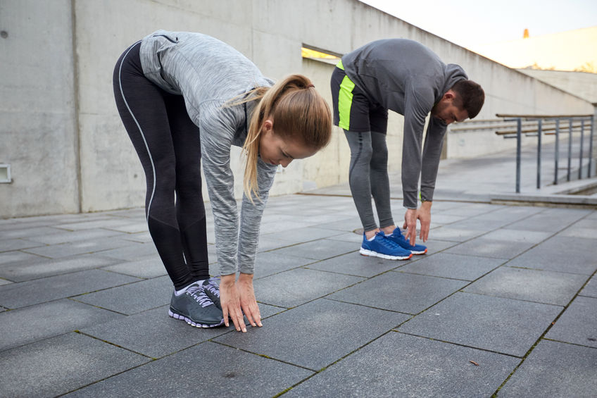 fitness 51225200 - fitness, sport, exercising, people and lifestyle concept - couple stretching and bending forward on street