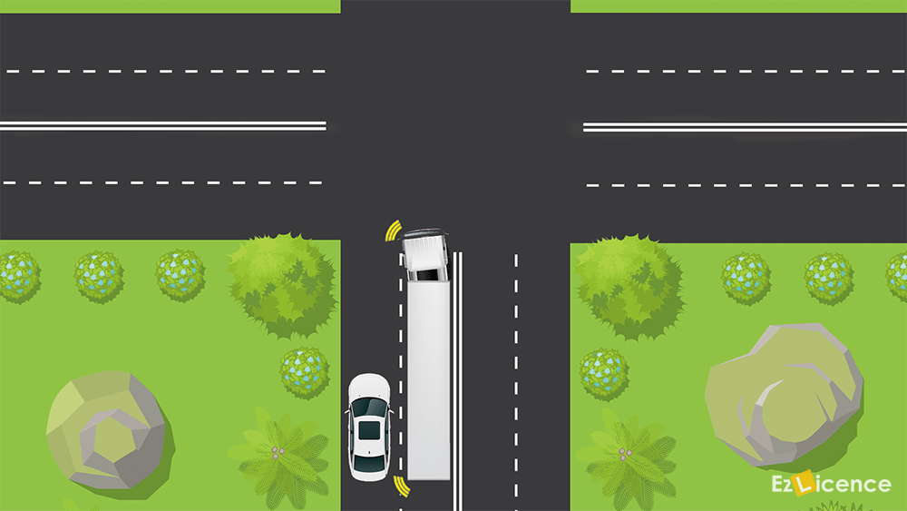 You are driving behind a long vehicle (as shown) which has a sign saying DO NOT OVERTAKE TURNING VEHICLE. The long vehicle indicates that it is going to turn left. You – 