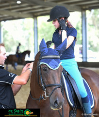 Jacinta Parry recieves assistance from Coach Matthew Lord setting up her earpiece during their dressage lesson on Saturday at Burpengary Pony Club Summer School.