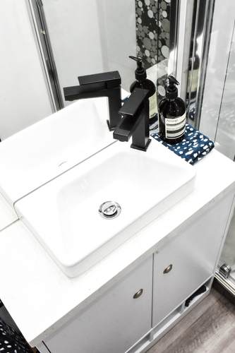 The bathroom vanity and shower have black matte hardware to match the kitchen. The truck holds 745L of fresh water over three tanks, 250L of gray water and 200L of black water.