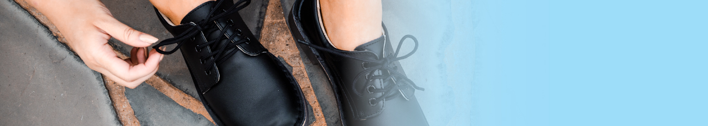 Close-up of Everflex black womens leather shoes as a woman ties the laces, highlighting stylish and durable leather shoes for women and elegant ladies leather shoes design.