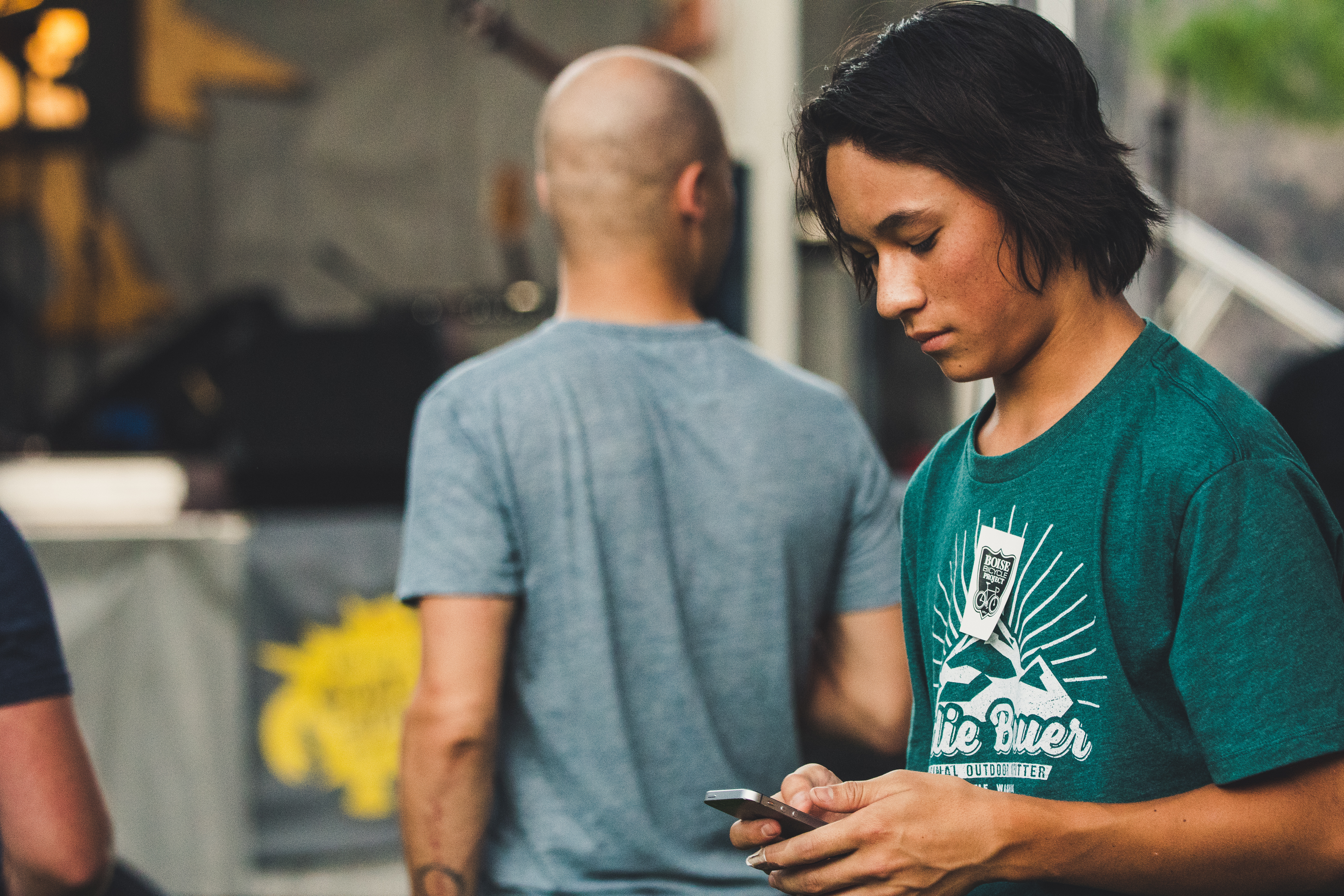 young teenager in green shirt looking down at phone