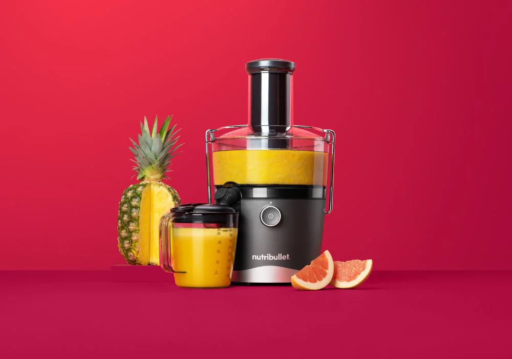 A Nutribullet air fryer on a kitchen counter with cooked food around it.