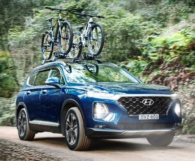 Santa Fe with bicycles trapped to its roof racks driving through the forest image