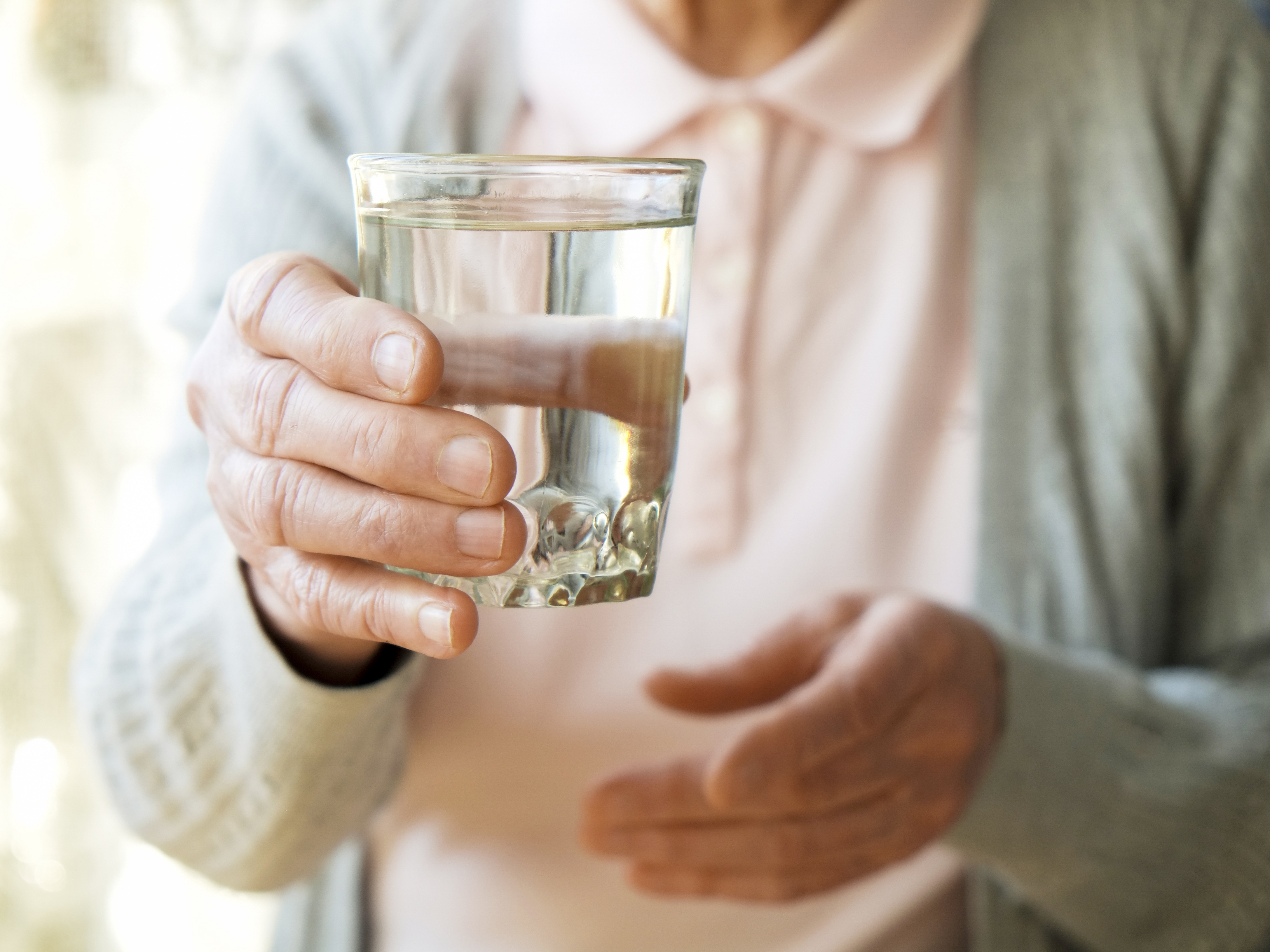 Woman holding a glass of water.