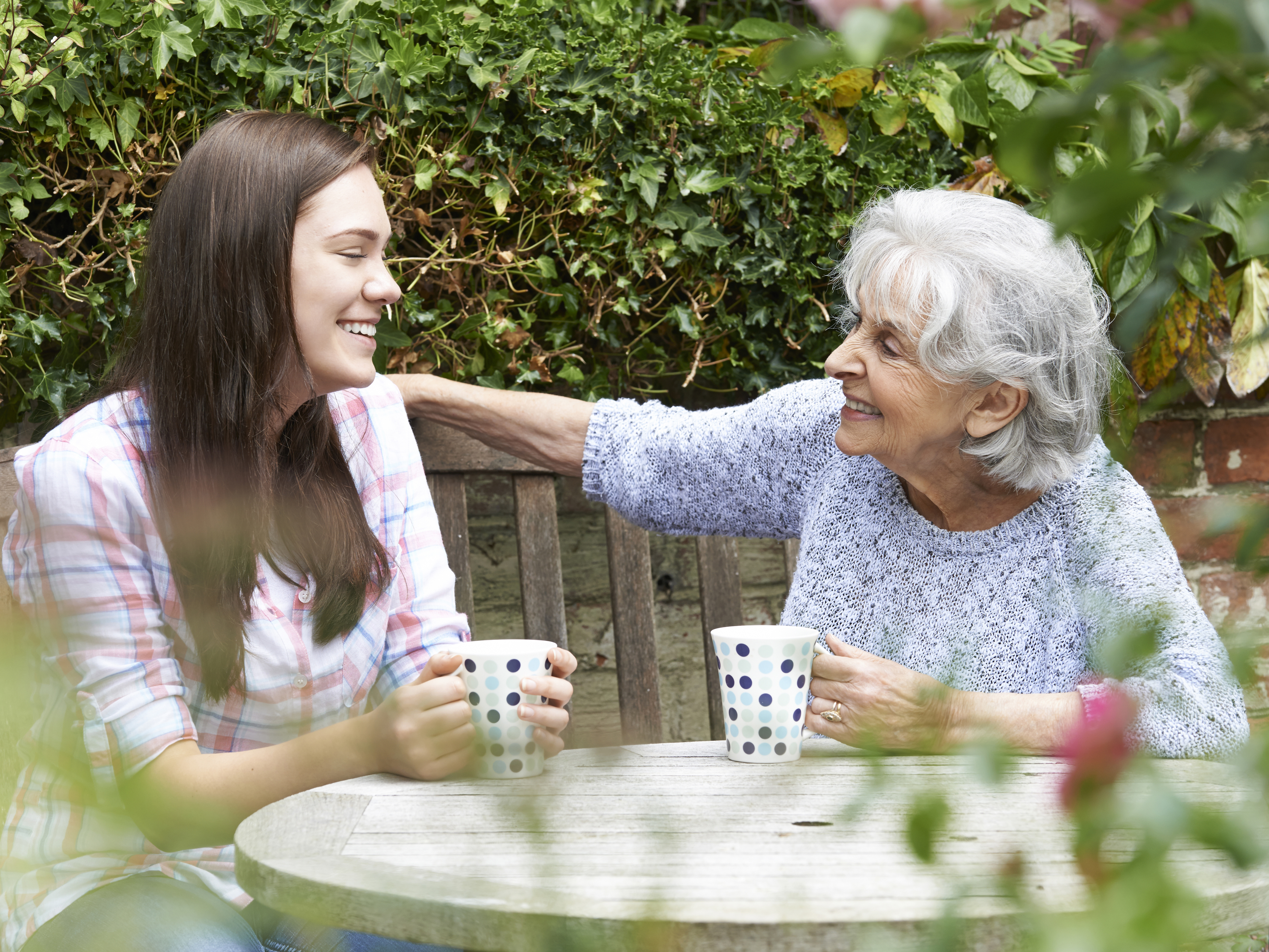 An older woman having a cuppa with a person.