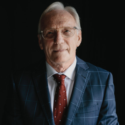 Garry Traynor smiling while wearing a navy suit and red tie