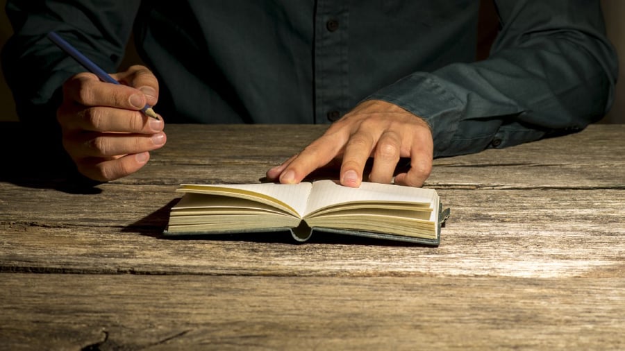 Man sitting at his work desk about to make a note in his notepad