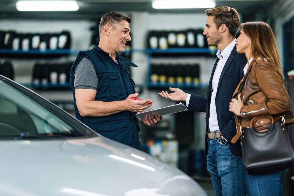 Technician talking with two customers about their tyres.