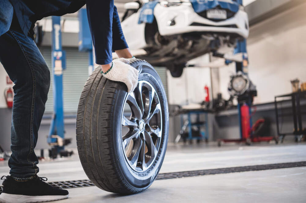 Technician removing a worn tyre from a car.