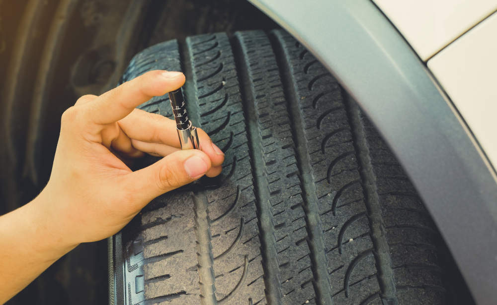 Person holding a tread depth gauge assessing the tread of a tyre.