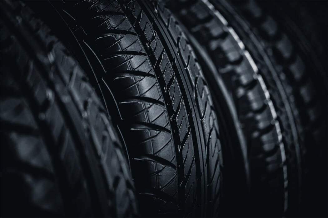 Close-up of several black car tires different tread patterns in a dark setting