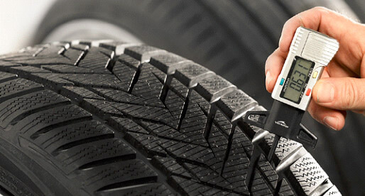 Hand measuring tire tread depth with a digital gauge