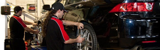 team of technicians performing wheel alignment