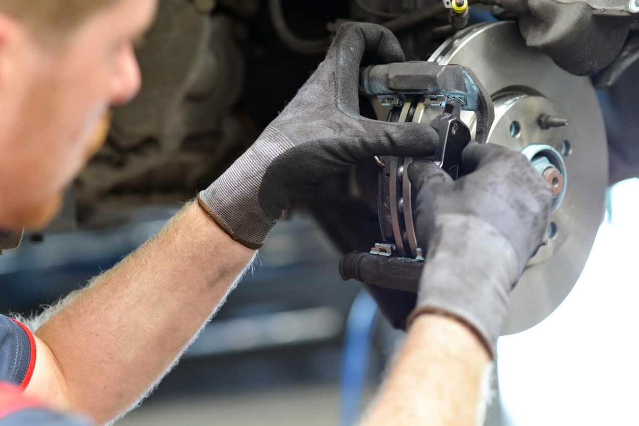 Technician replacing brake pads on car