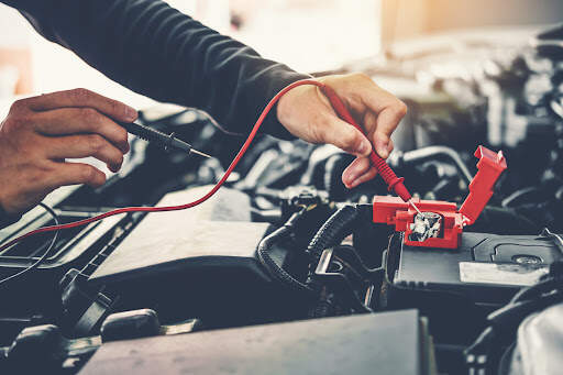 Your car battery is a very important component of your vehicle that supplies power to the starter motor and other parts. Technician hands of car mechanic working in auto repair service and maintenance car battery.