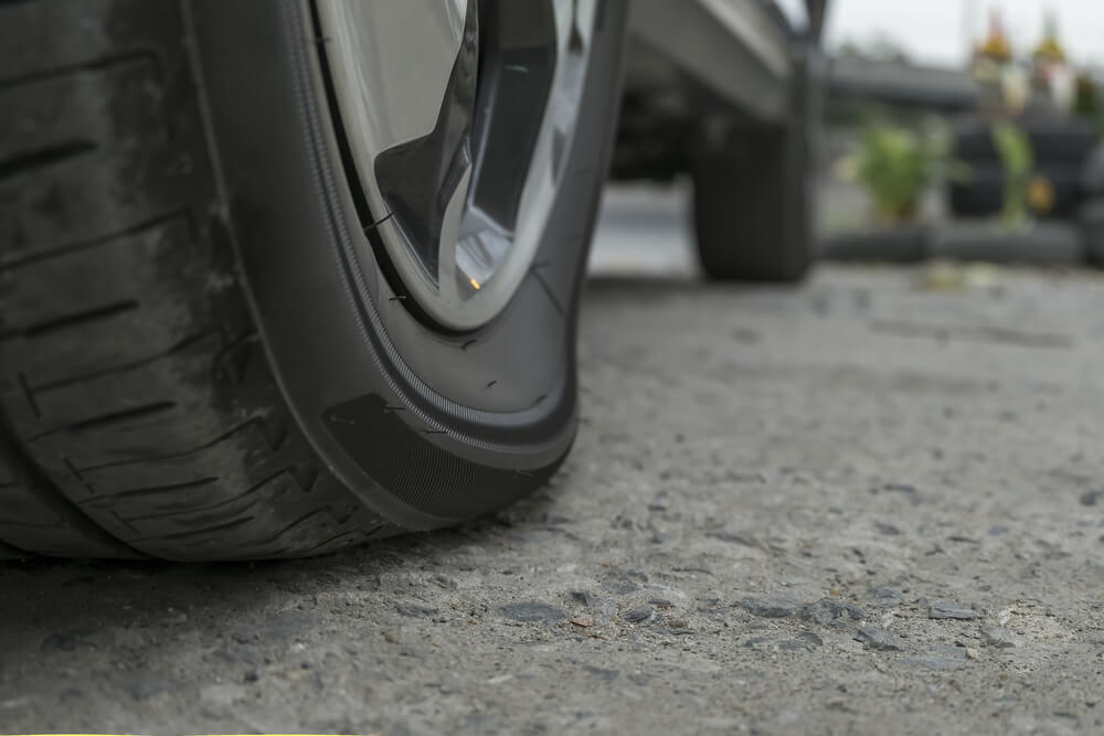 Under-inflated Tyre A car tyre bulging at the bottom because it’s under-inflated.