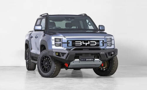 BYD Shark 6 off-road pickup truck in studio setting, fitted with all-terrain tyres and heavy-duty front bumper
