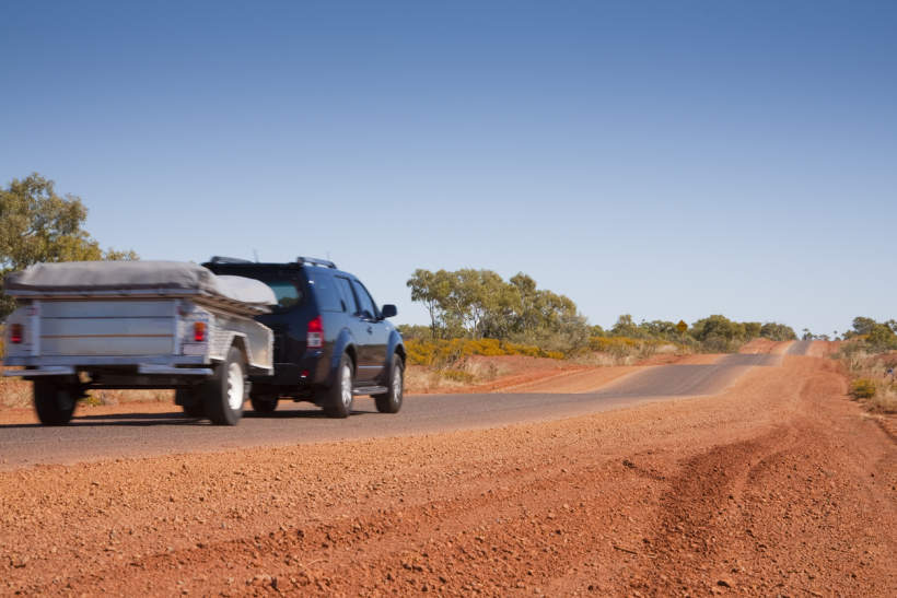 SUV towing camper trailer along rural road