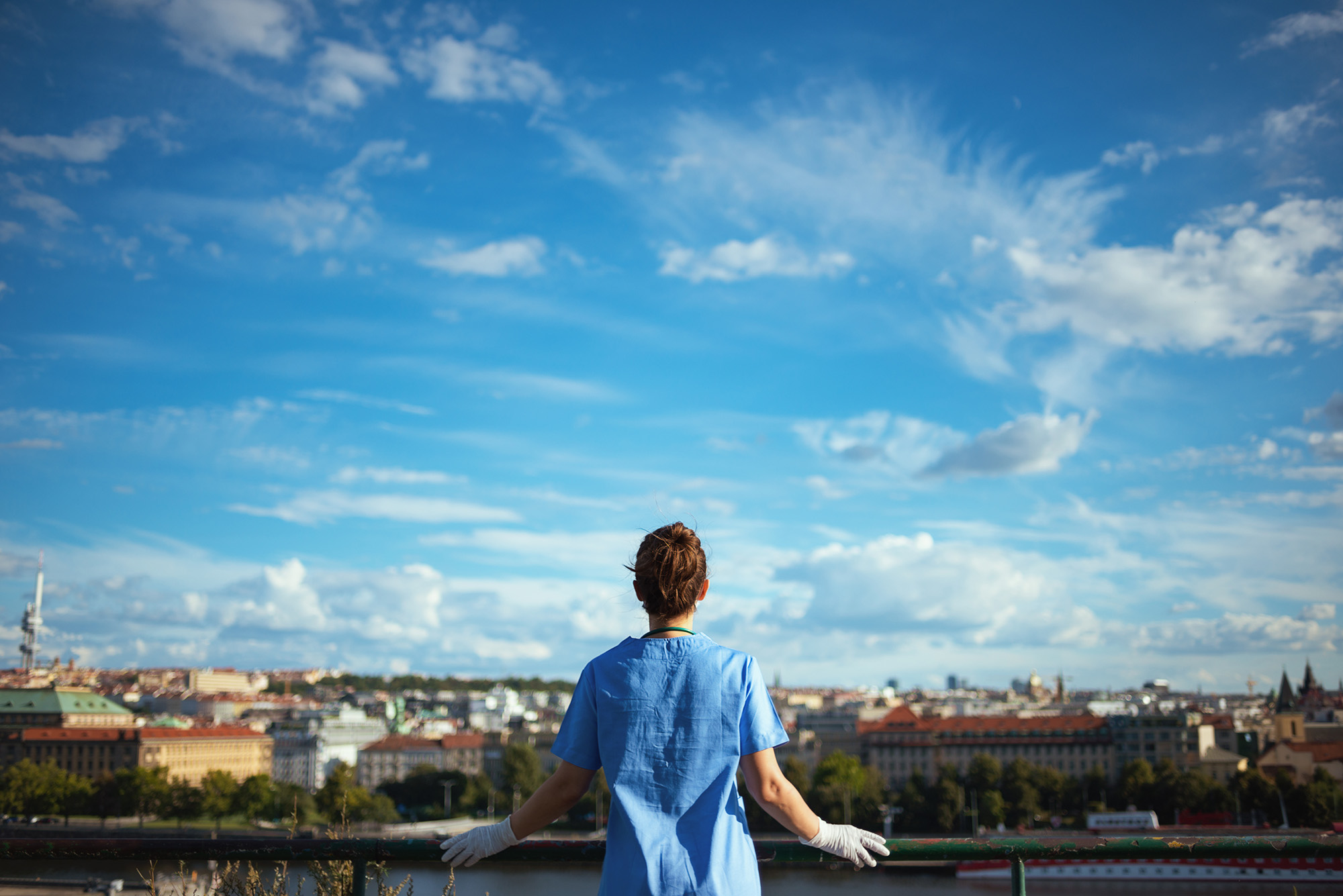 Clinician in scrubs looks out over the city