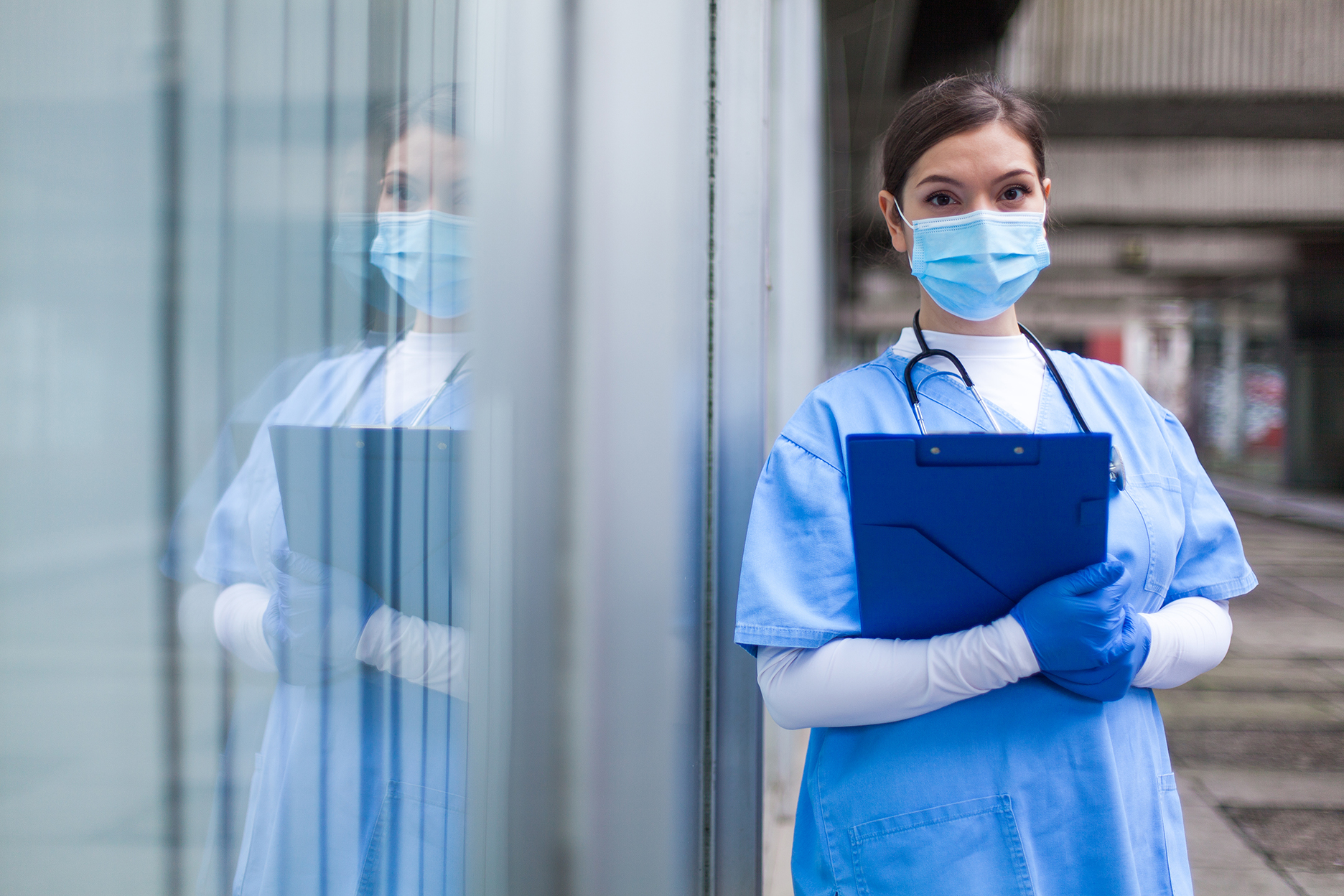 decorative image: nurse in scrubs and surgical mask with clipboard