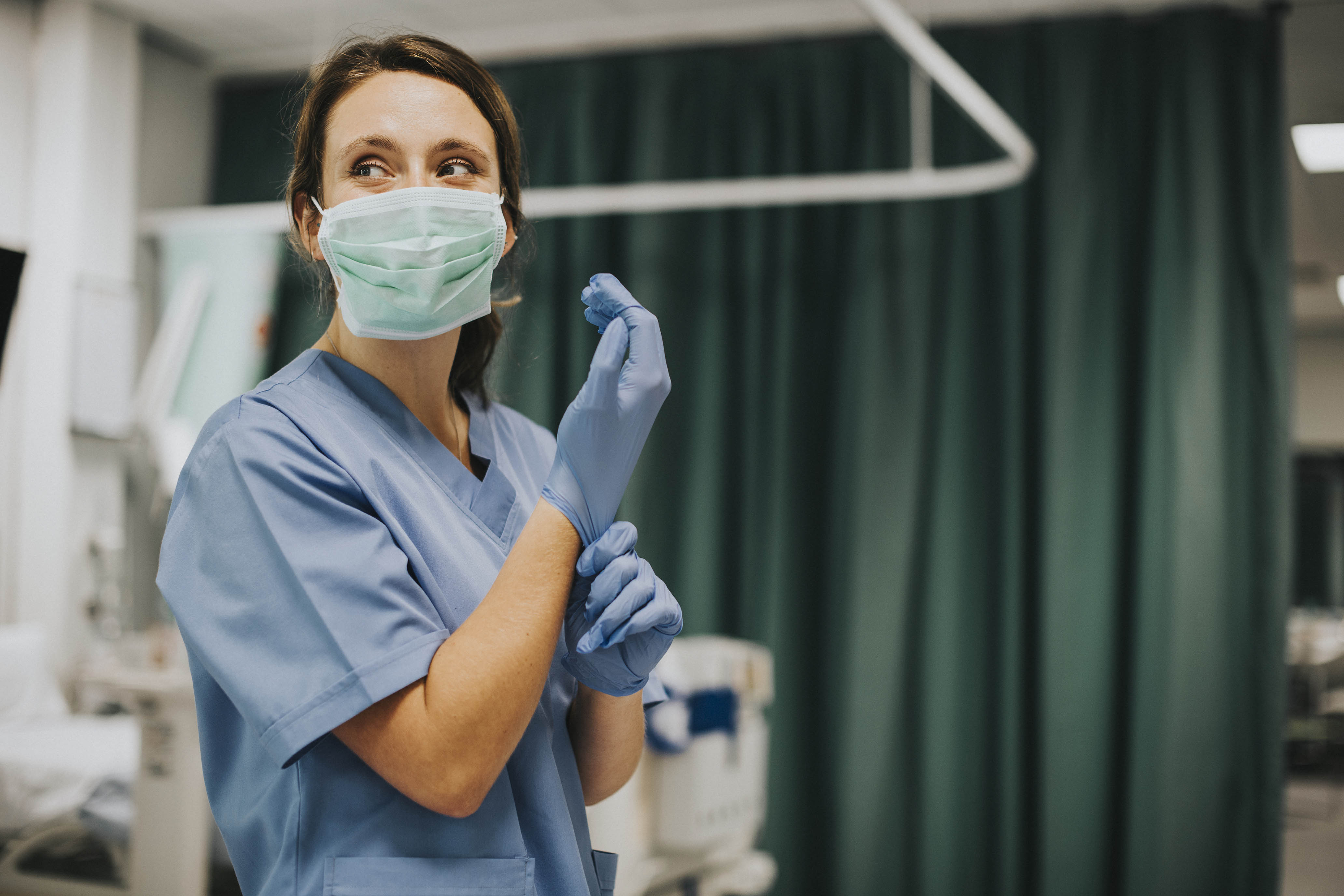 Busy masked nurse puts on gloves