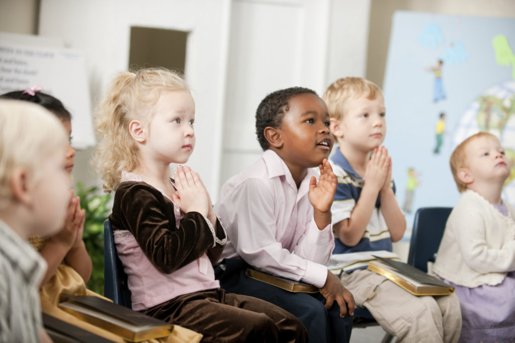 A group of multi-ethnic children at Sunday School in a real church classroom. Very shallow focus on girl's left eye.