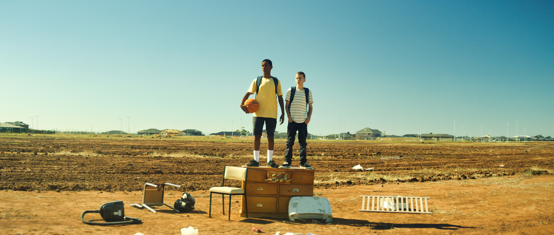 Two men standing on top of suitcasesDescription automatically generated with medium confidence