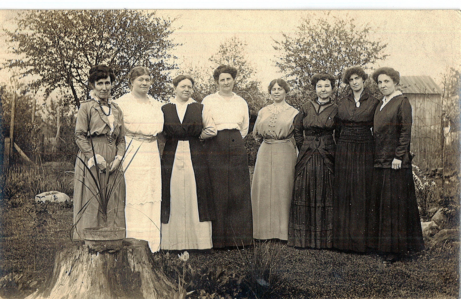 An old, black and white photo of a group of women standing together outdoors, in front of a backdrop of trees - from the Kalamazoo Public Library McConnell collection