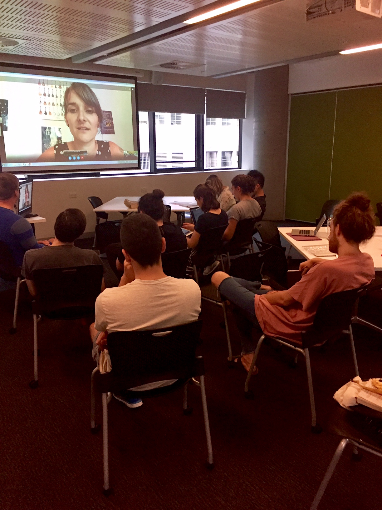 A classroom full of students watching a teacher on Skype.
