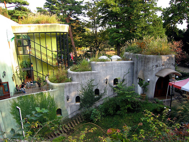 An external shot of the Studio Ghibli museum in Japan, a grey concrete building covered in green vines.