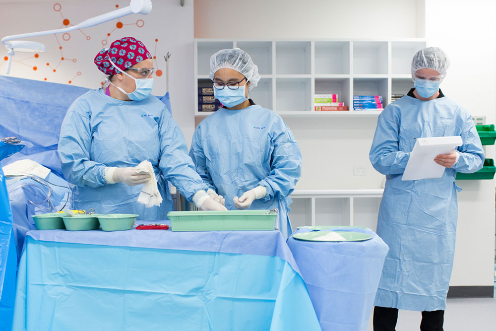 Students in scrubs counting and recording surgical instruments