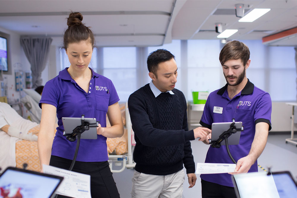 Two students in uniform learning with iPads from instructor