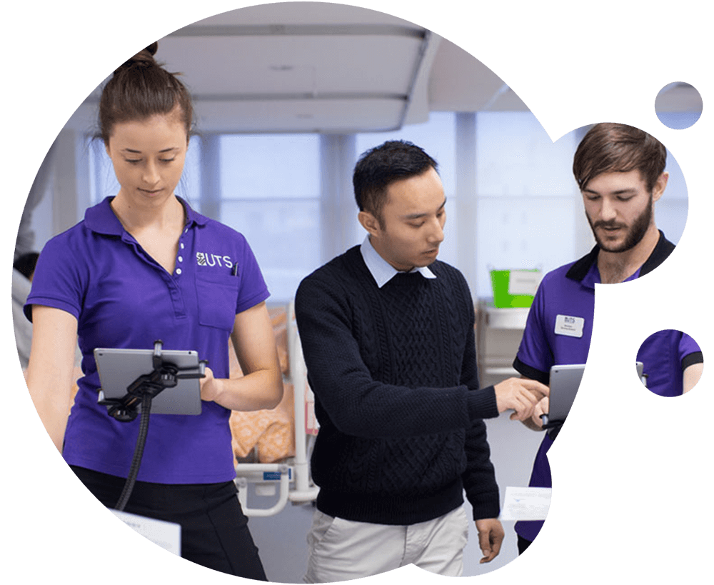 Two students in uniform learning with iPads from instructor