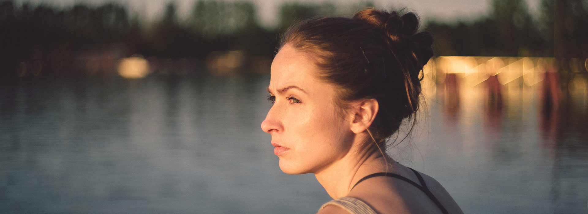 A side profile of a young woman looking pensively out towards the water.