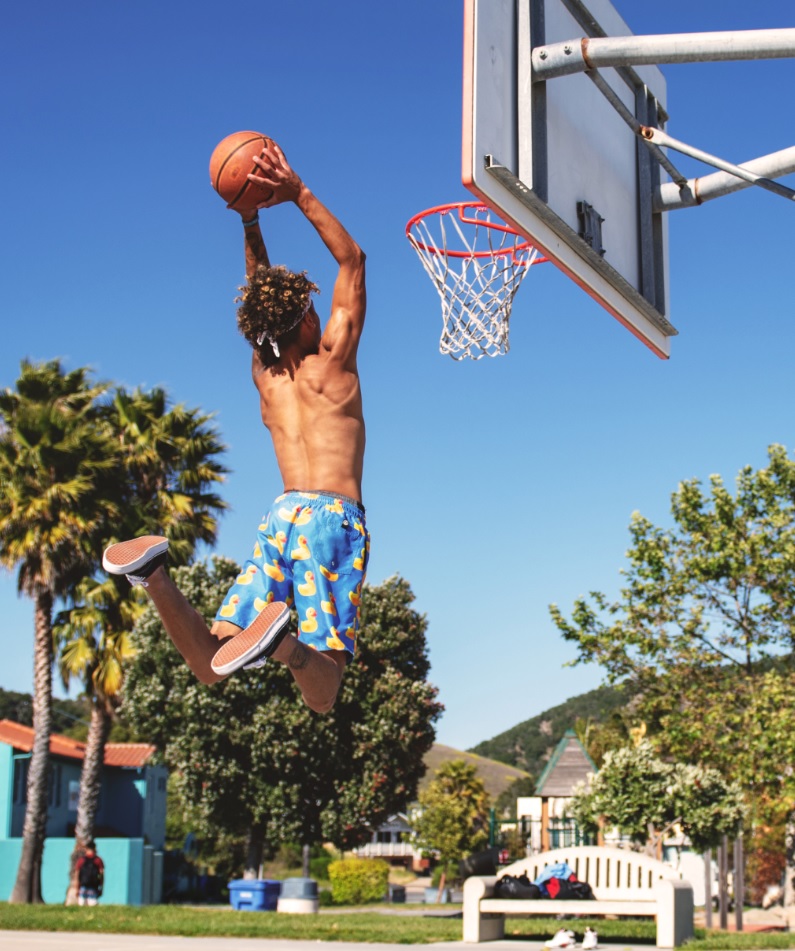 young man shooting basketball through hoop